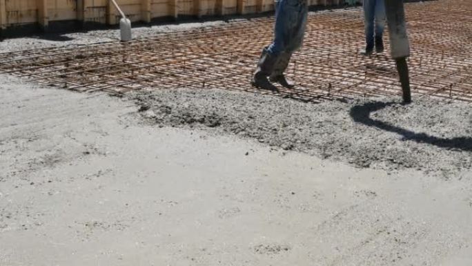 将混凝土砂浆倒入大型场地的加固基层的过程。建造者用加固网解决方案引导混凝土载体的管套均匀填充