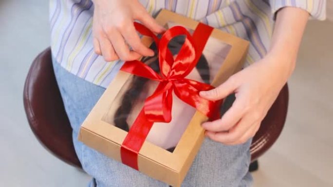 女人用天然切割辫子在礼品盒上解开丝带，捐赠理发