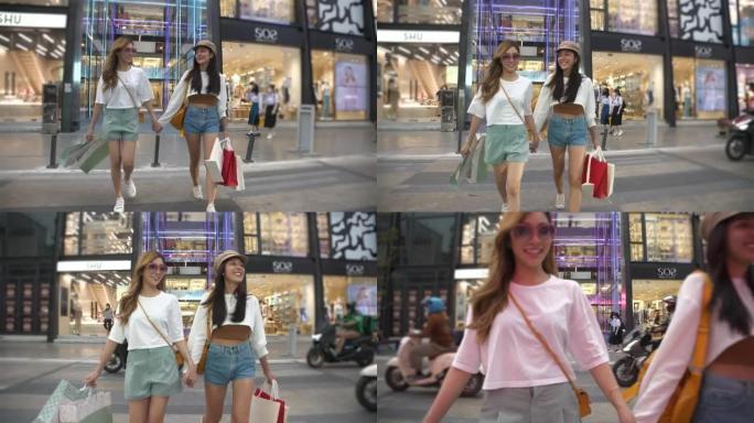 美丽的亚洲女孩在泰国曼谷快乐地带着Sopping bag行走。一位女性朋友正在街对面逛街。