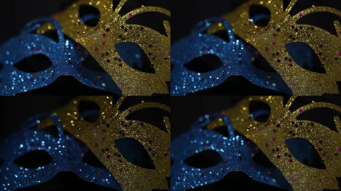 黑暗背景上的两个豪华传统威尼斯面具照亮并从黑暗中闪闪发光。蓝色和金色闪亮的狂欢节化妆舞会幻想面具，在