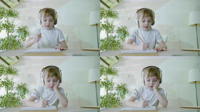 开朗可爱的小女孩戴着耳机听音乐，轻声唱歌，独自玩铅笔画画。