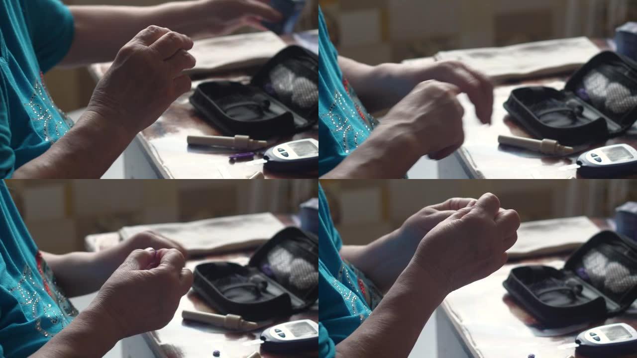 一位退休妇女的手在家里坐在桌子旁用血糖仪测量血糖水平的特写镜头。一名老年妇女监测糖尿病的glucom