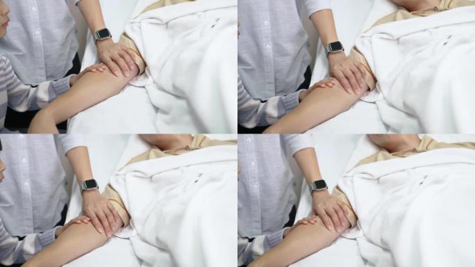 年轻的亚洲男孩担心地触摸他生病的父亲的手臂。