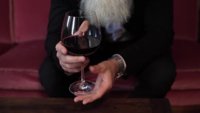 英俊的大胡子老人喝红酒