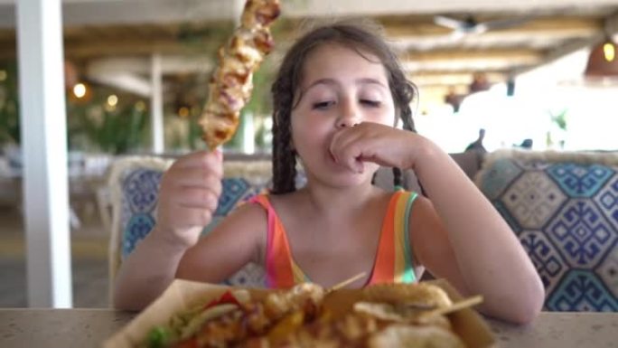 饥饿的白人女孩在餐厅吃羊肉串的画像
