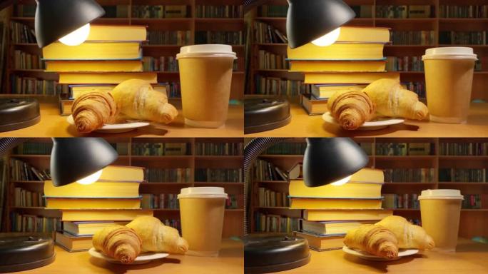 书籍，咖啡，羊角面包和灯在图书馆的桌子上旋转，在黑暗的房间里的书架上旋转。教育和学习理念