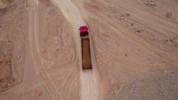 露天矿的沙子运输。自卸车在露天矿中运输沙子和砾石，无人机视图。