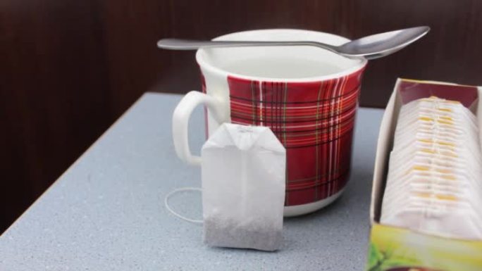 杯子和茶包。茶包的包装。喝茶。一杯水和茶包。