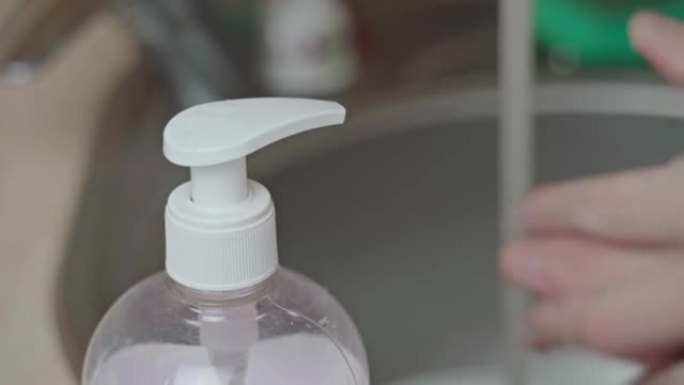 男子推分配器和液体肥皂挤出手，特写镜头和洗手。男孩在浴室洗手，使用柔软的凝胶进行高级皮肤护理