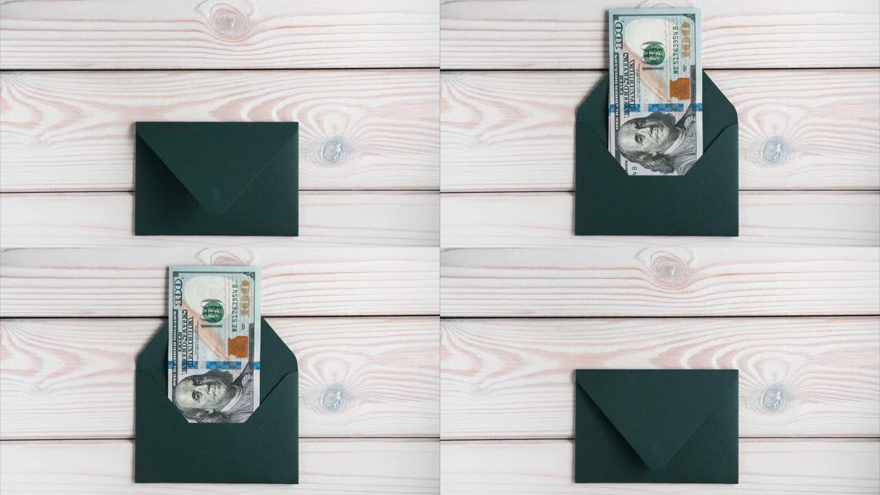 封闭的绿色信封出现在灰色的木桌上，打开。从信封中散开的百元钞票。