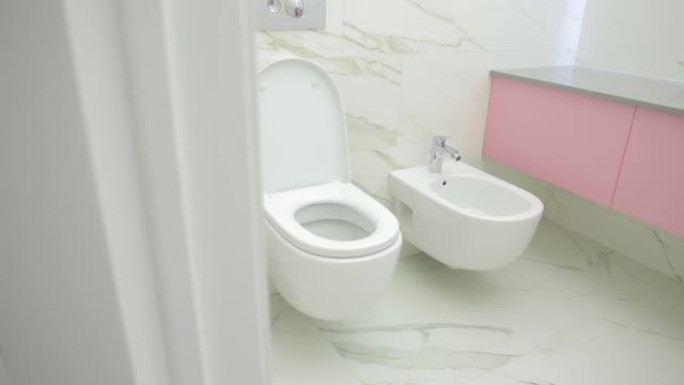 美丽的现代浴室内部配有白色瓷砖、水槽、卫生间和坐浴盆。现代照明镜子。