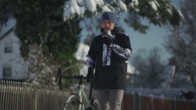 在寒冷的大雪天气中，冬天骑自行车的人停下来使用手机，在骑自行车的同时使用app查找GPS定位，路线引