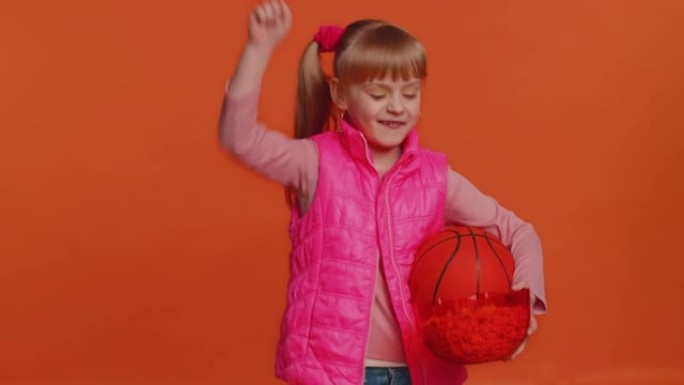 蹒跚学步的年轻女孩篮球迷吃爆米花做赢家手势，庆祝胜利