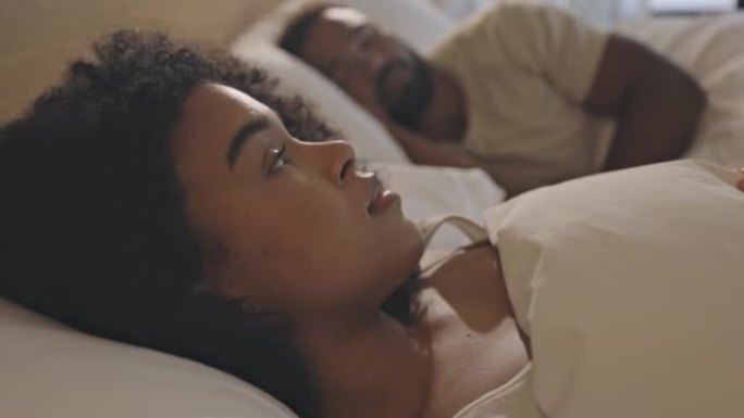 一个女人躺在床上清醒，丈夫睡觉时患有失眠和抑郁症。焦虑和情感的妻子在考虑关系破裂或离婚时感到孤独和迷