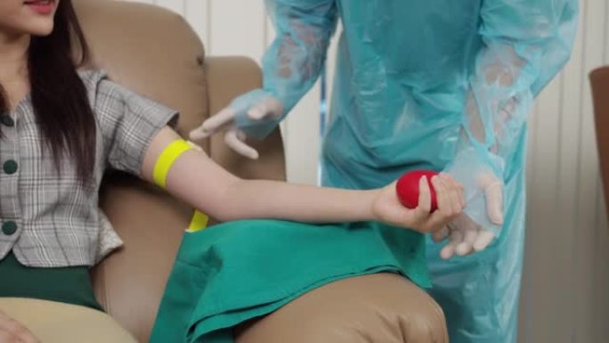 医护人员的特写镜头向献血者展示了如何在输血中心挤压球。