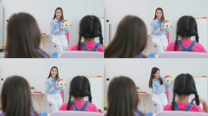 亚洲美丽的年轻女子老师在学校给孩子上课。有吸引力的女性讲师大师在幼儿园的教室里通过有趣的活动来解释和
