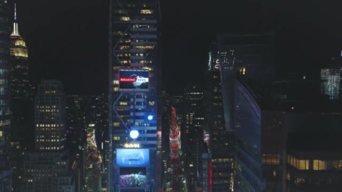 夜间市中心高层建筑的空中下降镜头。视觉效果在立面上添加大屏幕。美国纽约市曼哈顿