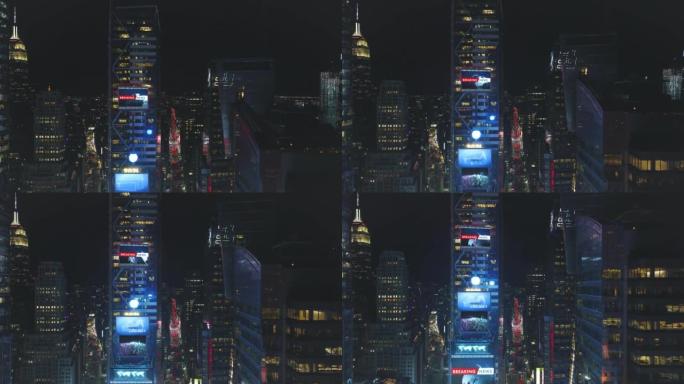 夜间市中心高层建筑的空中下降镜头。视觉效果在立面上添加大屏幕。美国纽约市曼哈顿