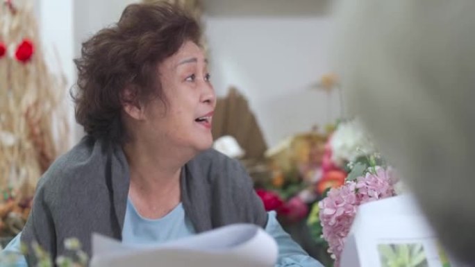 亚洲华裔高级女性学习阅读彩图搭配插花概念