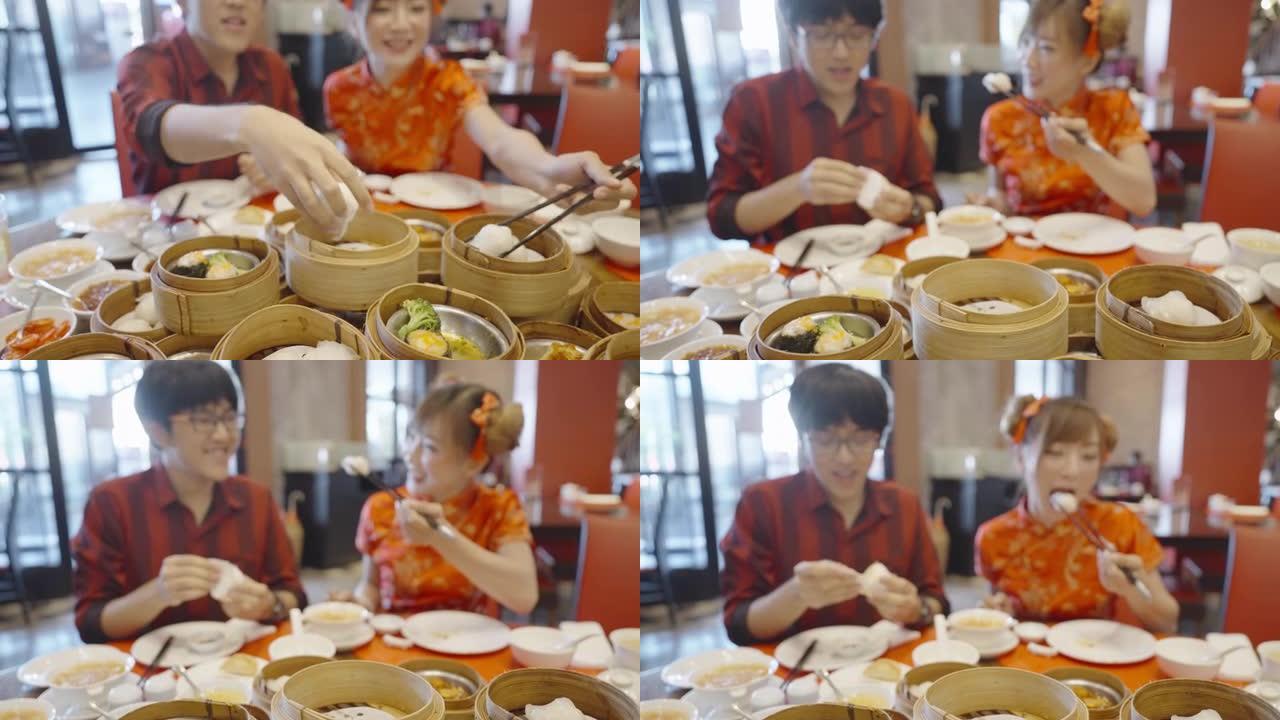 一对可爱的夫妇在一家中餐馆共进午餐，吃点心庆祝农历新年，一对用手，另一对用筷子。