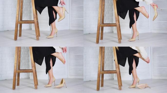 Lady takes off beige high-heeled shoe and feels re