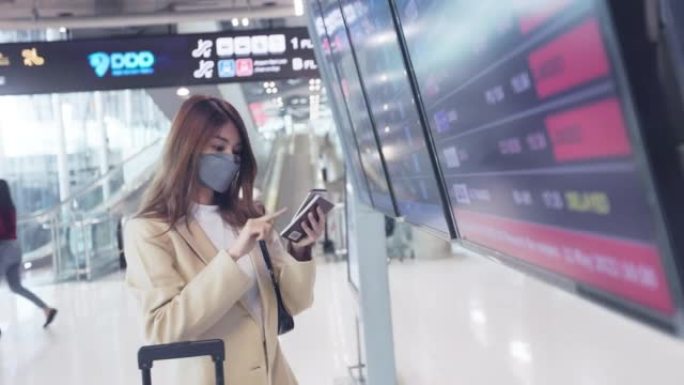 年轻的亚洲女商人在机场的登机牌前阅读登机牌。商务旅行概念。