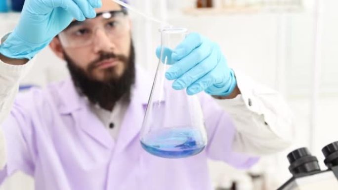 科学家将溶液放入实验室烧瓶中。使瓶子里的蓝色水变成紫色。摇动装有化学药品的瓶子。在实验室工作的科学家