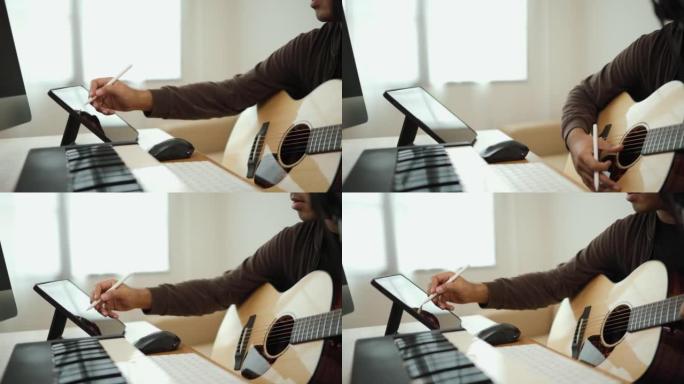 特写手专业歌曲作者弹吉他和钢琴键盘与平板电脑混合和掌握音乐。男在录音室用音响设备创作歌曲。音乐家概念