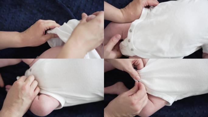 母亲的双手用白色连体衣打扮新生婴儿男婴的特写镜头