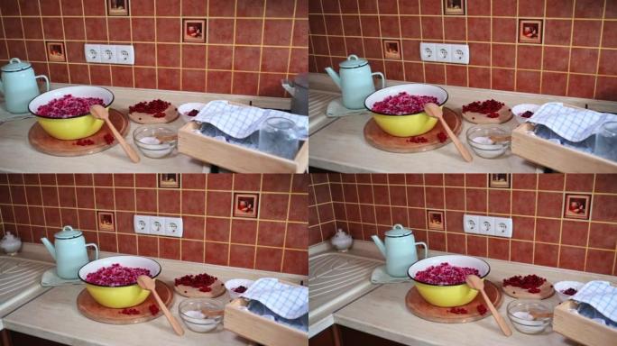 厨房台面上有满满是红醋栗的碗，上面撒上糖，水壶，木箱，上面盖着毛巾的灭菌罐，开水锅