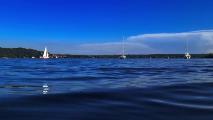 在意大利马焦雷湖平静开放的湖水中航行的小红船的极低角度视点