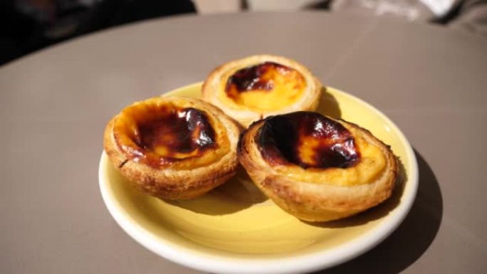 餐厅餐桌上的三个 “pastel de nata” 甜葡萄牙糕点食品的一部分