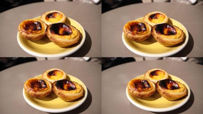 餐厅餐桌上的三个 “pastel de nata” 甜葡萄牙糕点食品的一部分