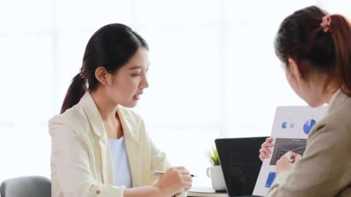 两名妇女坐在白皮书中交谈，两名商业妇女讨论头脑风暴和计划运营，结成伙伴关系，成立了一家初创公司。创业