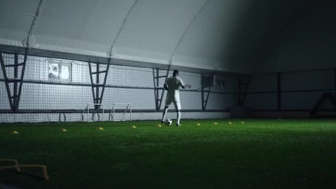 独自在室内体育场进行夜间训练的非裔美国足球运动员，练习运球