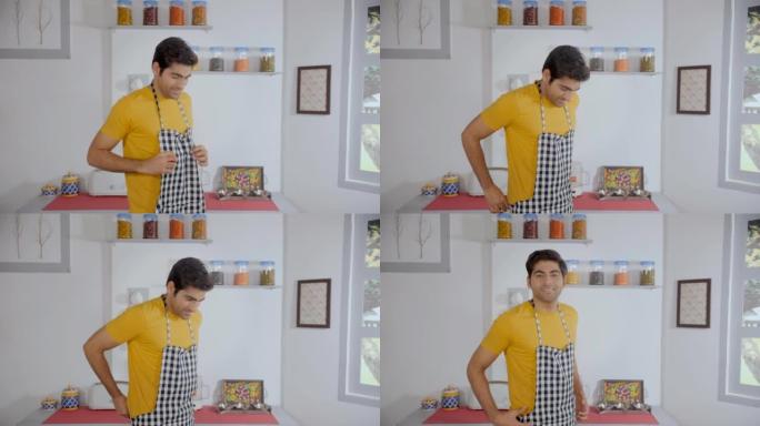 现代印度男子准备做饭并在厨房内系围裙