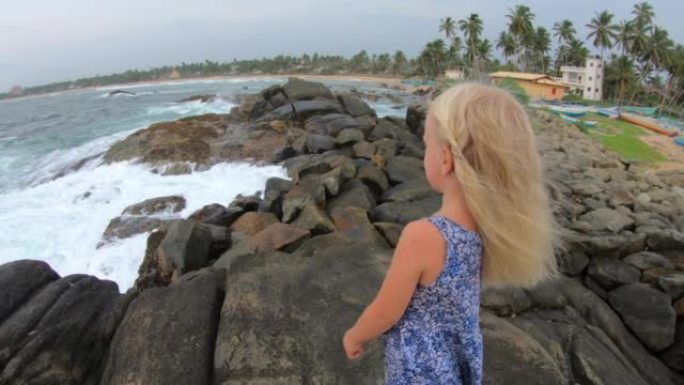 海边岩石海滩上的金发女婴享受日落围棋职业