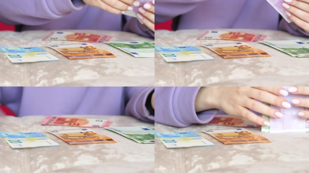一个女人在桌子上数着欧元现金的特写镜头。女性手中的面值为10,20，50，100欧元的纸币。财务问题