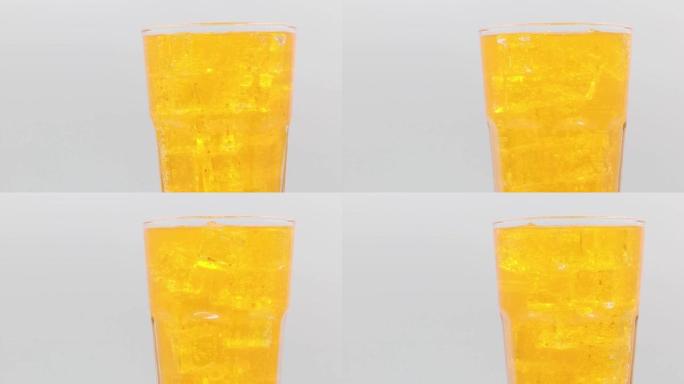 白色背景上的橙色苏打水和玻璃中的冰。