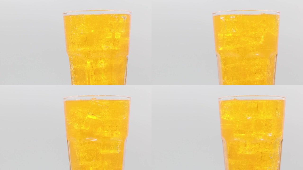 白色背景上的橙色苏打水和玻璃中的冰。