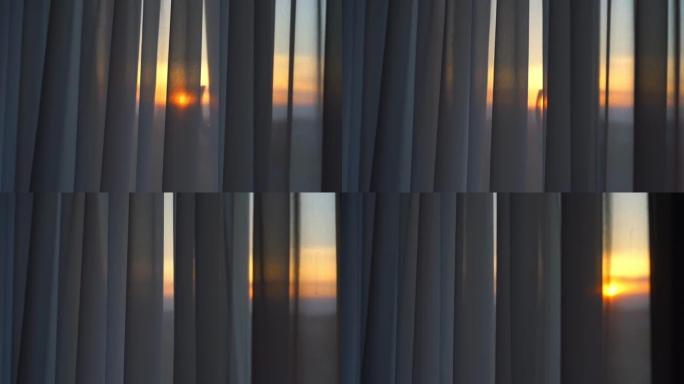 摄像机在日落时沿着悬挂在窗户上的透明窗帘移动