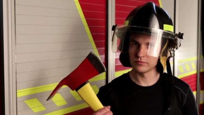勇敢的男消防员，戴着带面罩的头盔，手里举着一把斧头，自信地看着镜头。肖像。