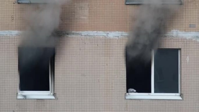 一栋公寓楼的两扇窗户冒出灰色浓烟。扑灭高层建筑的大火。公寓里着火了。