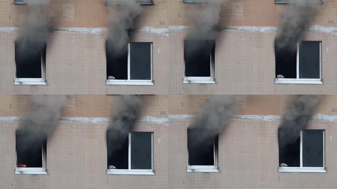 一栋公寓楼的两扇窗户冒出灰色浓烟。扑灭高层建筑的大火。公寓里着火了。