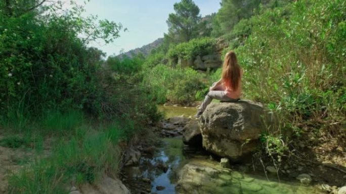 女人坐在石头上享受大自然。