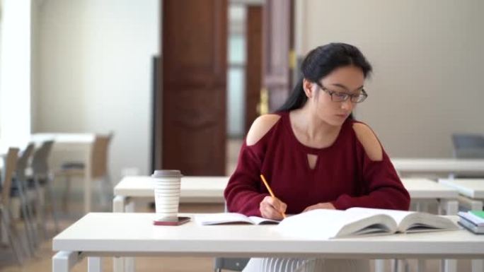 体贴的中国学生女孩在课本上写笔记，集中准备考试