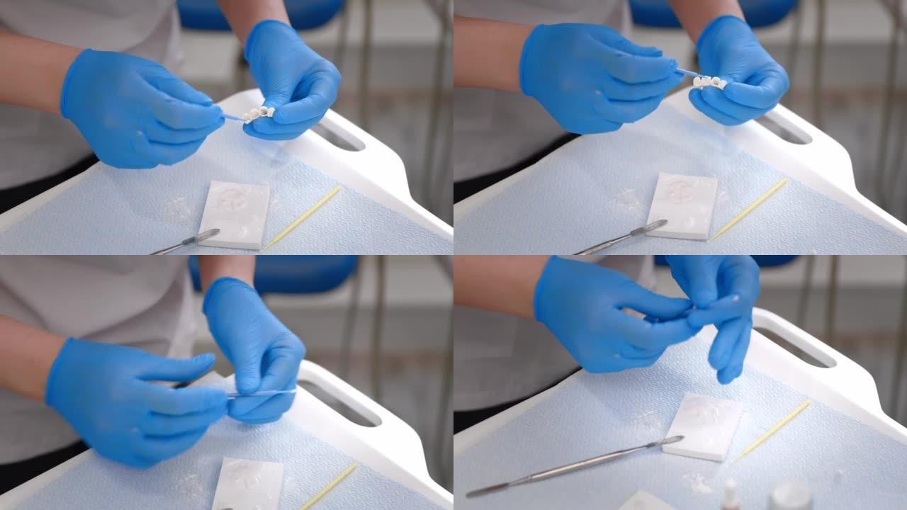 牙医戴着医疗手套的手在医疗办公室与牙科植入物和牙冠一起工作