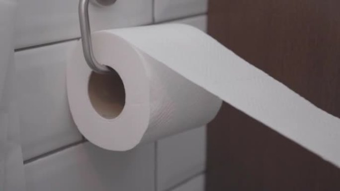 用手从厕纸上取几张纸。
