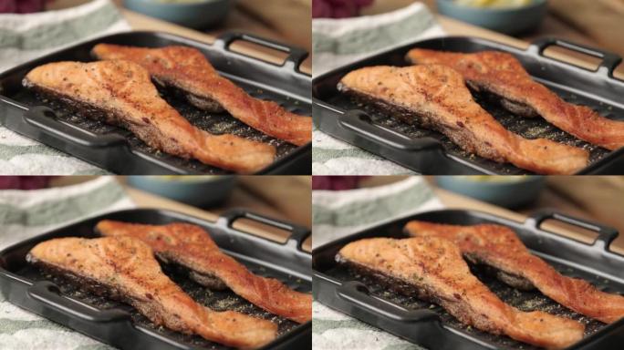 慢动作4k视频，烤烤鲑鱼片在撒上欧芹或莳萝的黑色盘子上。鲑鱼健康饮食和高蛋白质饮食