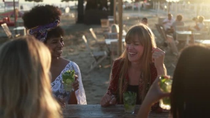 年轻的多种族女性在户外海滩派对上喝莫吉托鸡尾酒，背景是日落